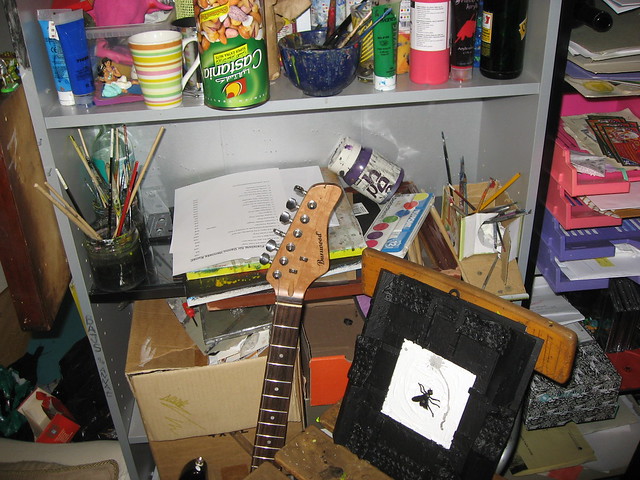 The creative mess of my studio in Vienna messy stuff and a 3d artwork and the icon guitar and an art prize-list and even an Ottakringe bottle