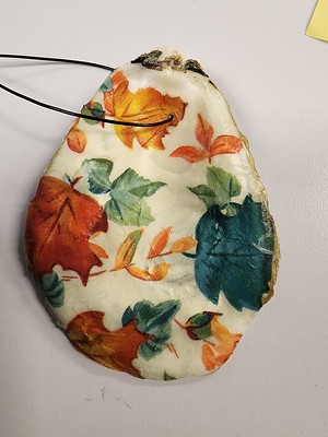 Photo of an oyster shell with fall colored leaves, that range from red, orange, and green.