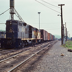 5/12/79, CS GP9 6463 Chessie GP9 6463 and a GP7 pull a long string of cars west out of the yard at New Castle, PA  while a group of railroaders and GP30 6959 looks on.