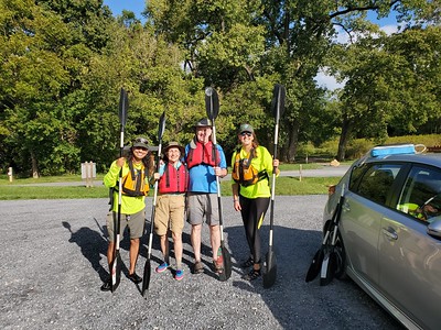 Friendly park staff and guests stand with their paddles and pfds before a program. 
