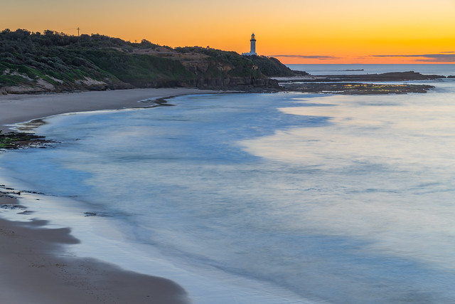 Sunrise seascape with lighthouse in the distance