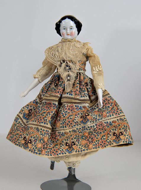 Doll w/ china head, blue eyes & multi-color skirt