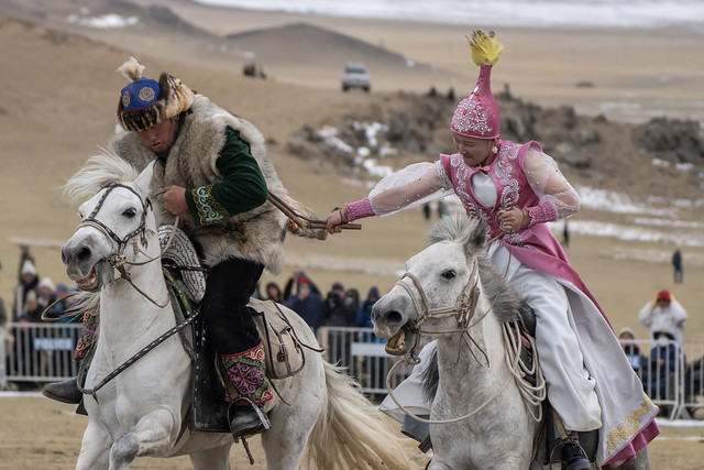 Woman whipping partner at Ulgii Golden Eagle Festival, Mongolia