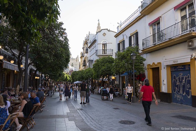 Ihmisiä kadulla ja ravintoloiden terasseilla Sevillassa