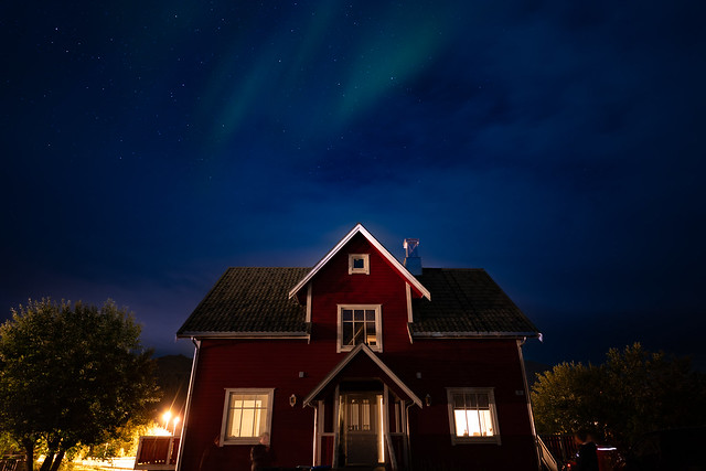 Red wooden house with northern lights