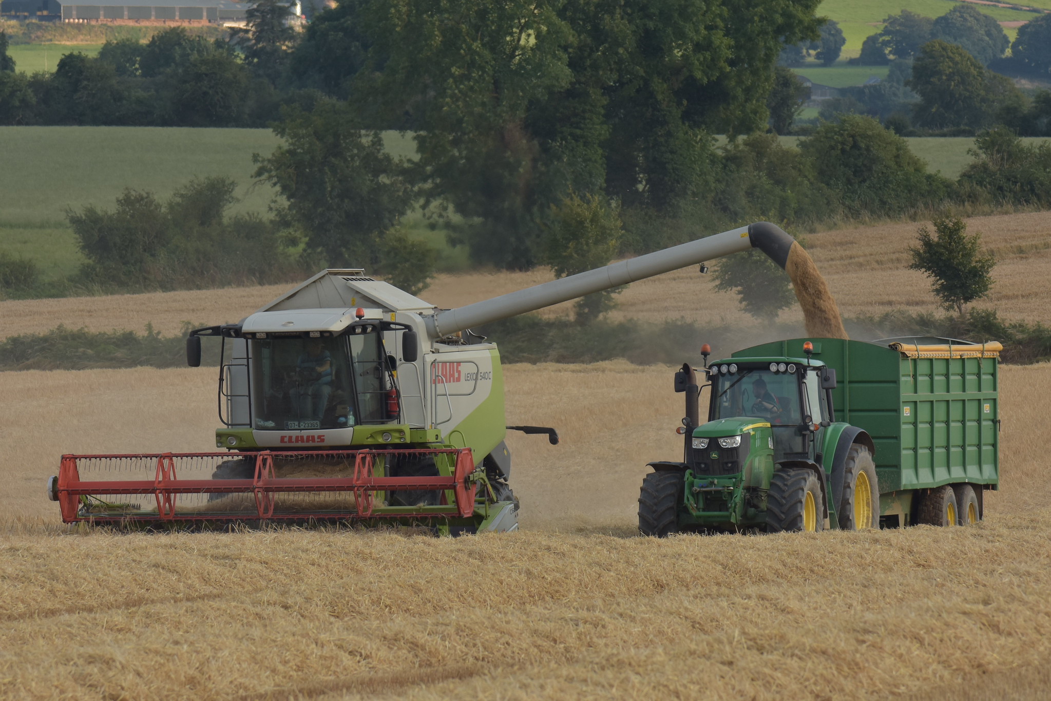 Claas Lexion 540 C Combine Harvester unloading Winter Barley to a Smyth Trailers Grain Trailer drawn by a John Deere 6150M Tractor