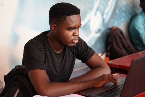 A young black man wearing a black shirt looks at his laptop screen - How to Choose a Minor