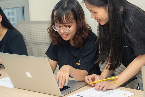 Two young women look at a Mac computer and smile - Learn About Your Post-High School Pathways