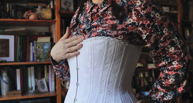 Une fine dentelle de coton blanc borde le haut du corset
