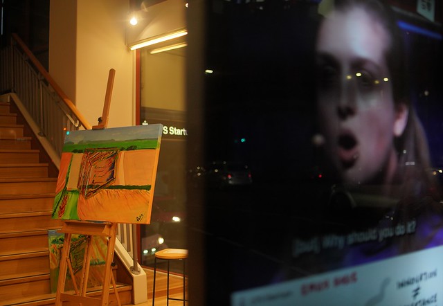 Painting on easel plus woman's face on a screen