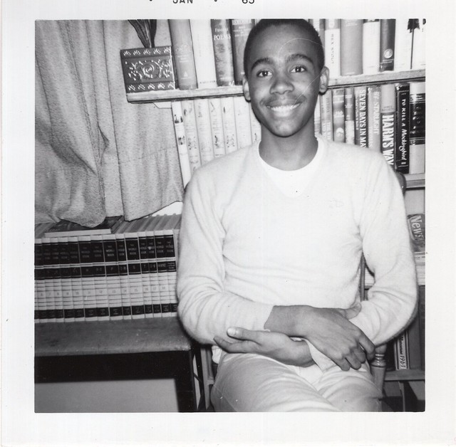Snapshot_portrait of smiling young man in front of encyclopedias and book shelf, 1965