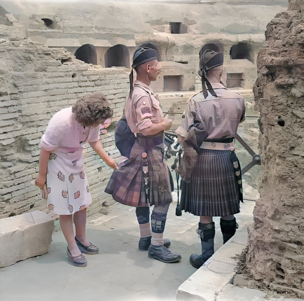 An Italian woman inspects the kilts of Pipe Major William MacConnachie and Pipe Major William Boyd in the Colosseum of Rome, 6 June 1944.