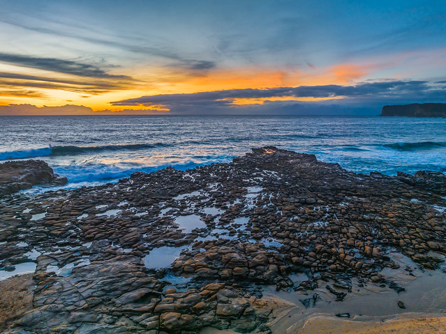 Sunrise over the sea and rock platform with high cloud