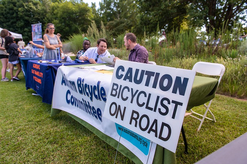 People sit at a table with signs promoting safe bicycling