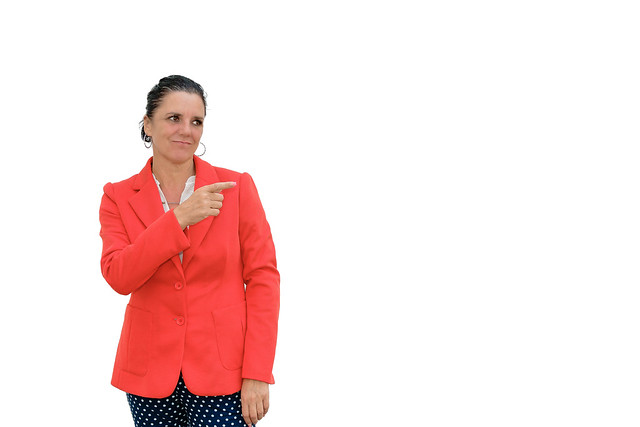 Woman pointing and looking to the side on white background.