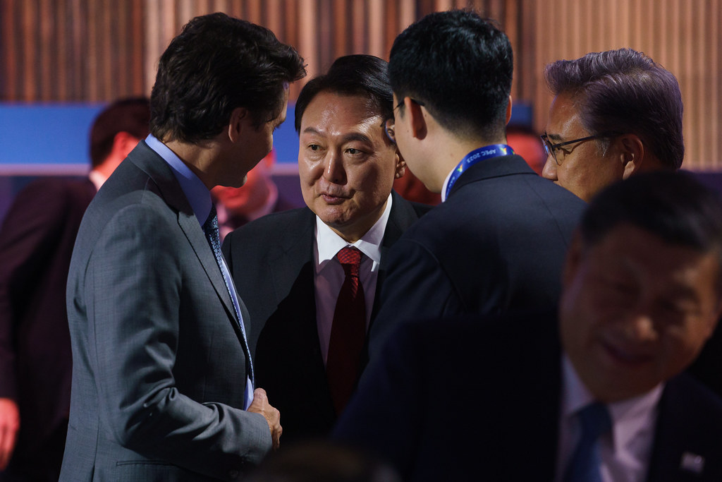 Prime Minister Justin Trudeau speaking with President of the Republic of Korea Yoon Suk Yeol. Other people standing with them. 
