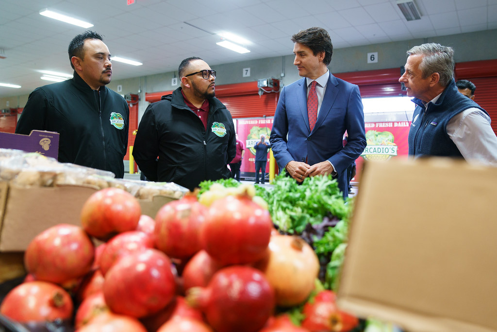 Prime Minister Justin Trudeau standing with a group of employees in front of fruits and vegetables