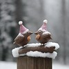 a couple of birds sitting on top of a wooden post, a photo, pixabay, folk art, snowfall, toy photo, high res photo, close-up photo, funny sculpture, festive, bottom angle, girls, 3 4 5 3 1, seasonal, santa, close-up, resting, dusting of snow, detaild, tou
