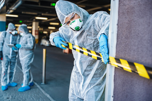 Healthcare worker cordoning off an urban area with barrier tape during an outbreak