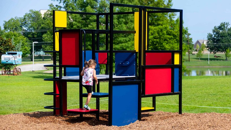 A young girl climbs on a colorful play structure