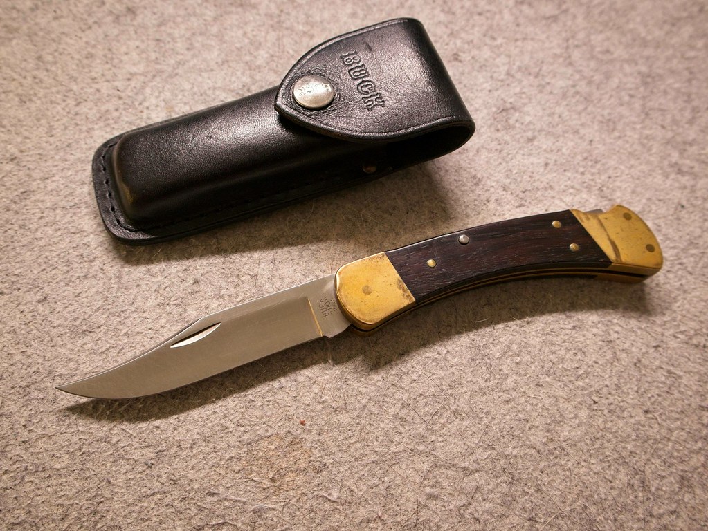 Buck 110 Folding Hunter Knife, dahinter Lederscheide aus Leder