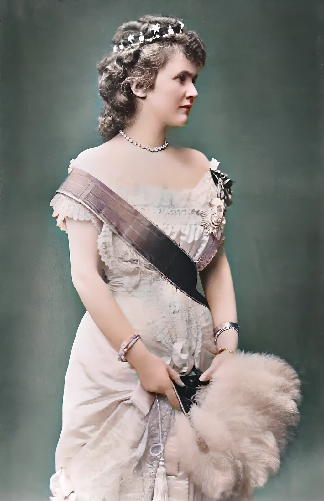 Elizabeth, Queen of Romania, holding a feather fan and wearing a Sash and insignia, a diamond necklace and a small head band, 1881