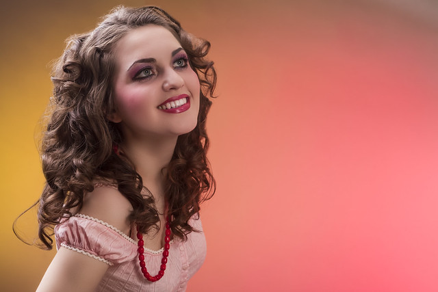 Closeup Portrait of Smiling Positive Sensual Young Caucasian Female in Colorful Clothing in Dolly Style Against Color Background