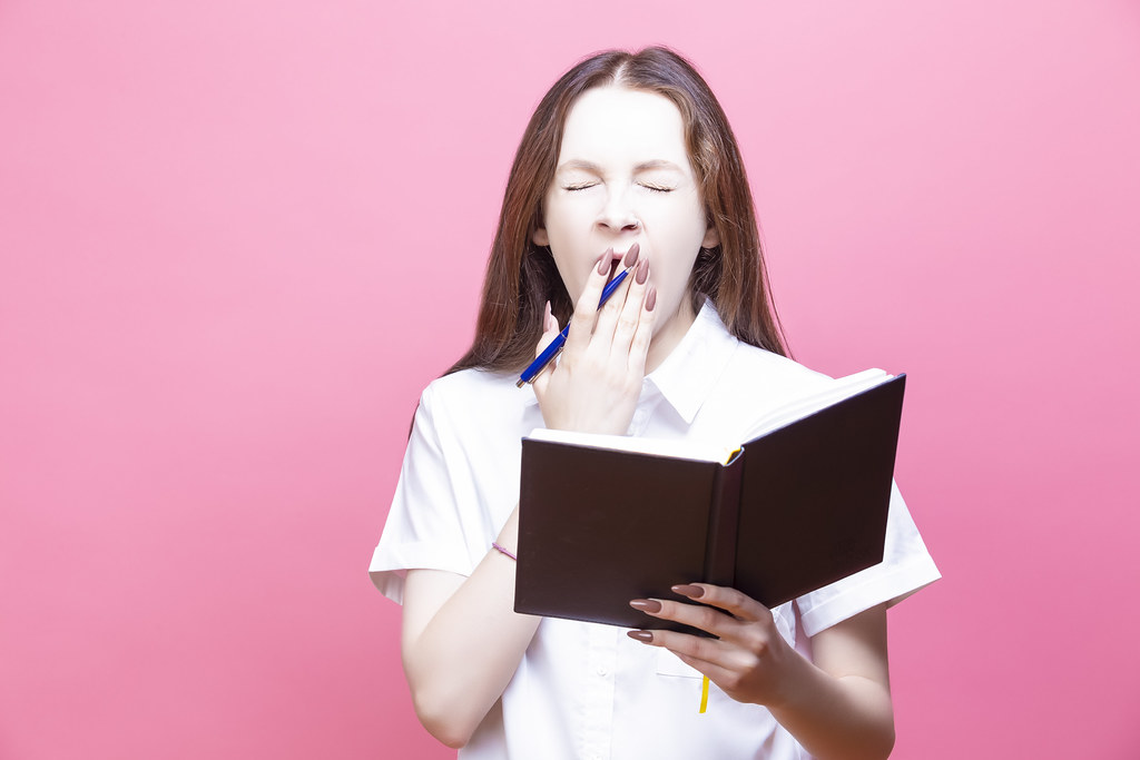 Young Student Woman Holding Notebook Over isolated Pink Background Bored Yawning Tired Covering Mouth With Hand