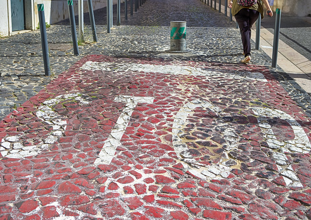 Portuguese Pavement Known as Calçada Portuguesa Made of Small White-Red-Black Stones in Mosaic Pattern With Stop Sign and Pedestrian