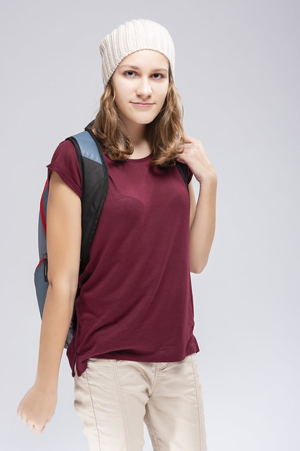 Teenager Lifestyle. Winsome Calm Caucasian Laughing Teenager Girl With Teeth Brackets Posing With Backpack Over White.