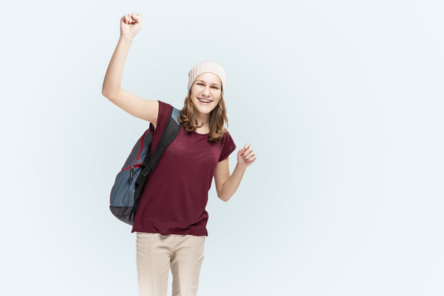 Teenager Lifestyle Ideas. Portrait Of Caucasian Laughing Teenager Girl With Teeth Brackets Posing With Backpack Over White.