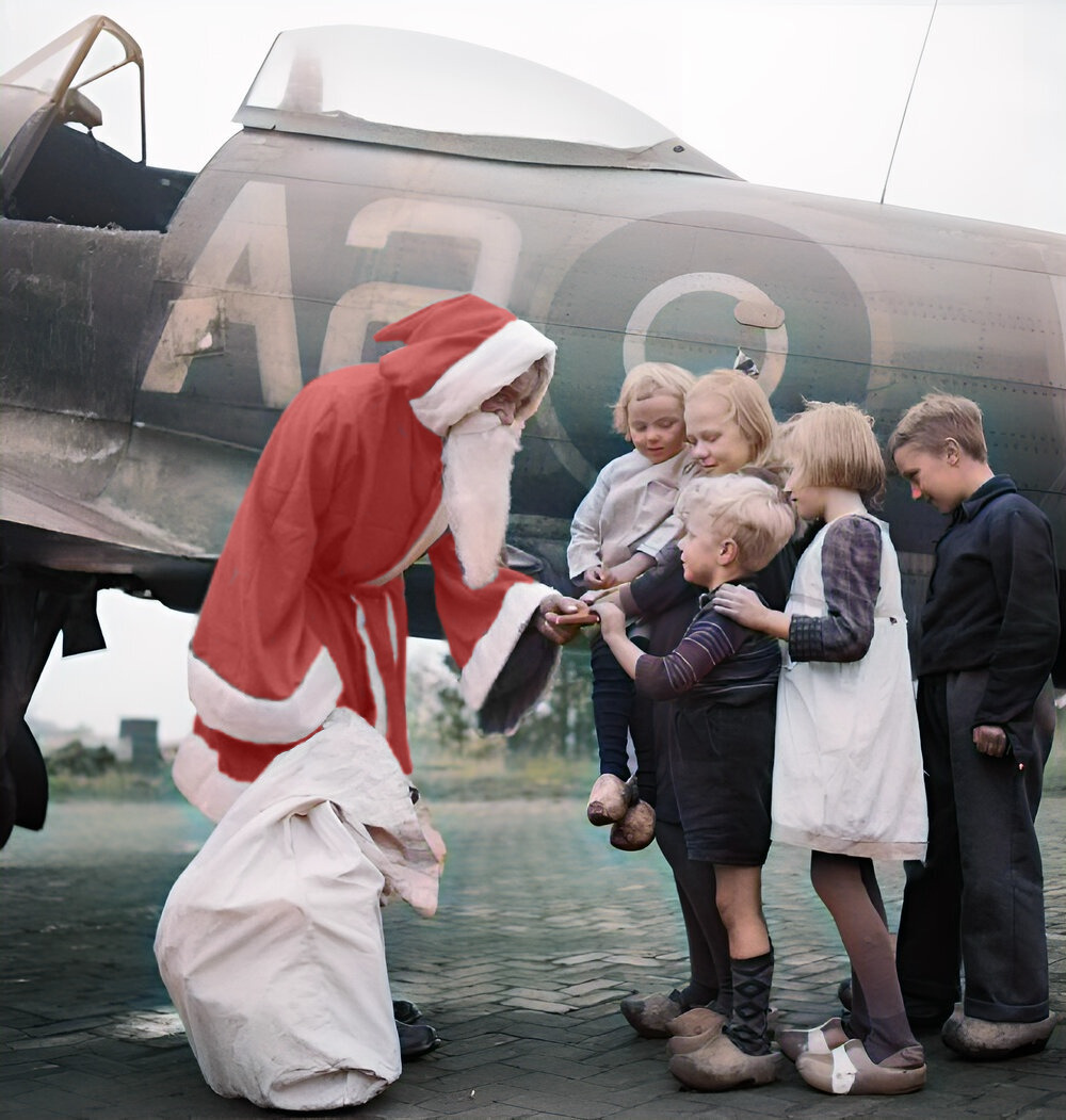 Leading Aircraftman Fred Fazan dressed as Santa Claus hands out presents to Dutch children at No. 122 Wing's airfield at Volkel, Holland, 13 December 1944