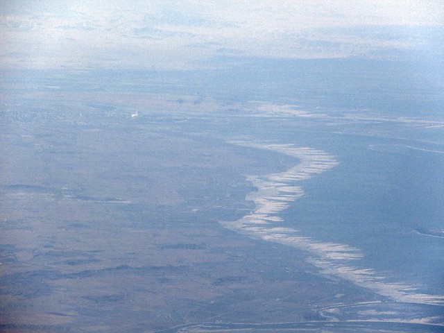 The Yalu River draining into Liaodong Bay and Sino-DPRK border. Dandong, China is left and Sinuiju, DPRK is right. All the mountains in the background are in North Korea. The icy coastline is China. Taken on a Seoul-bound flight.