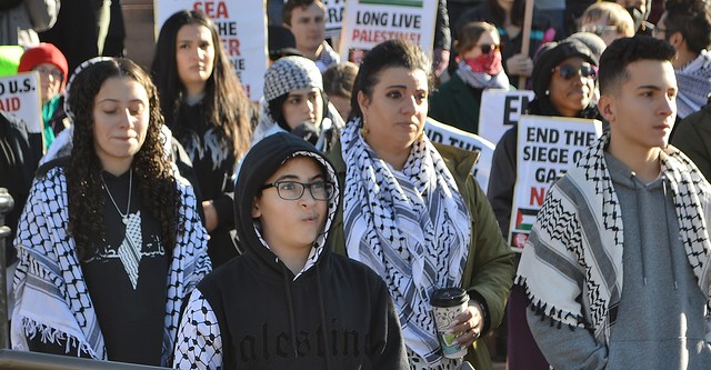 Protesters wearing the kaffiyeh listen to speakers at a rally against Israeli attacks on Gaza.