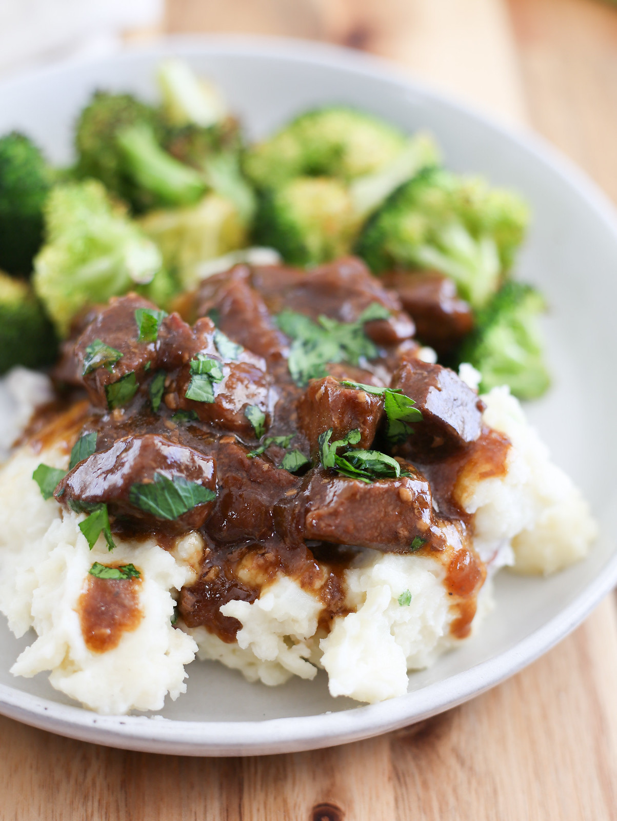 Slow Cooker Steak Bites served over mashed potatoes with gravy and parsley on top