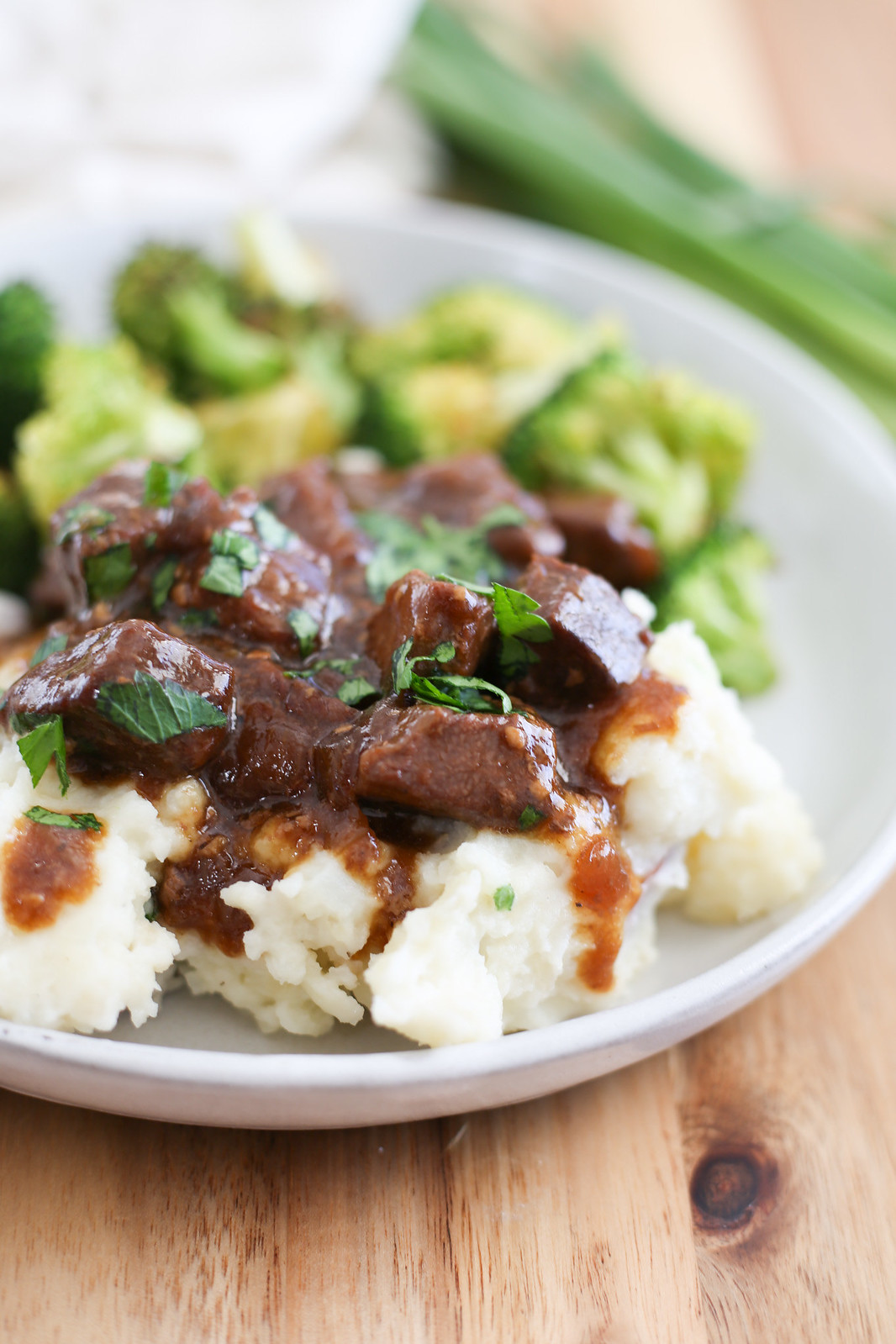 crockpot steak bites with gravy served over mashed potatoes with parsley on top