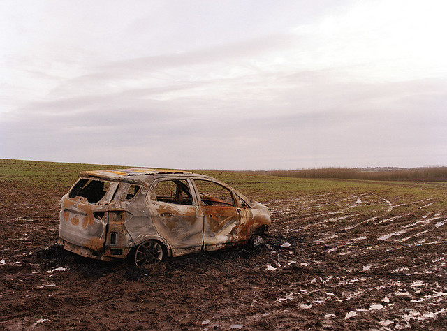 BURNT OUT CAR ON THE MUDDY FIELD