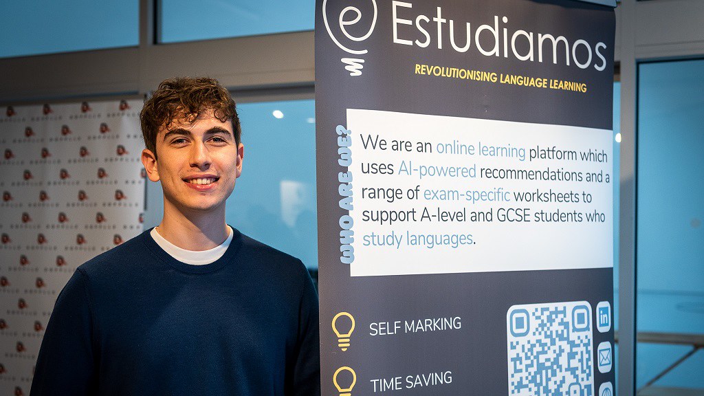 Student standing next to pull up banner that explains Estudiamos