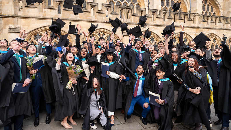 Graduates throwing their caps into the air outside Bath Abbey