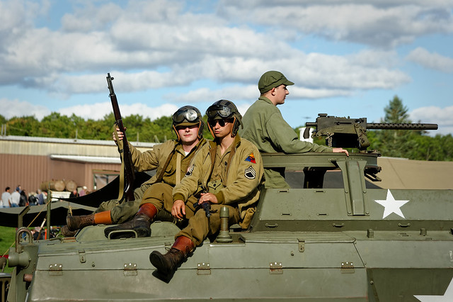 World War II reenactment soldiers riding back from battle on the top of a tank