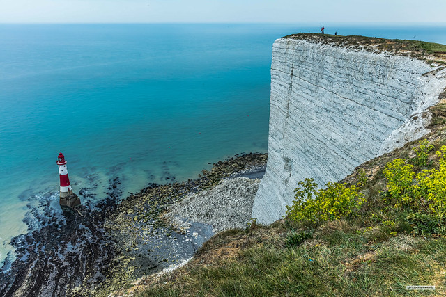 Beachy Head Lighthouse beyond the headland with its 550 foot chalk cliffs, East Sussex, England.