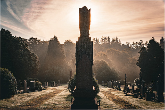 Morming sun behind a large grave stone, Lochwinnoch Cemetery, Lochwinnoch, Renfrewshire, Scotland, UK