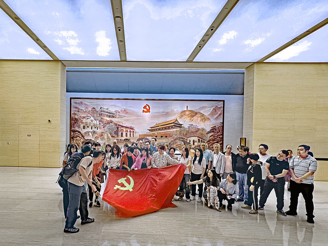China 2023. Shanghai. Group posing behind a Red Flag after having visited the CCP Museum.