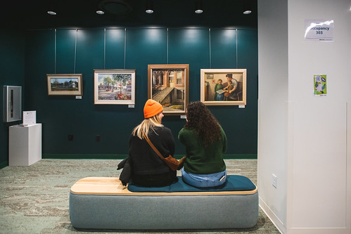 Two people seated in the community art wall