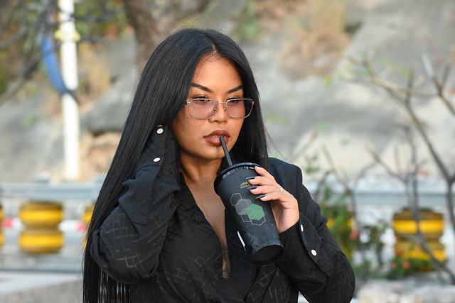 DSC_4614: a woman with glasses holding a drink and talking on a cell phone