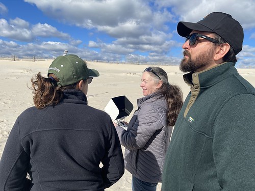 Photo of three people watching a drone flight from the beach