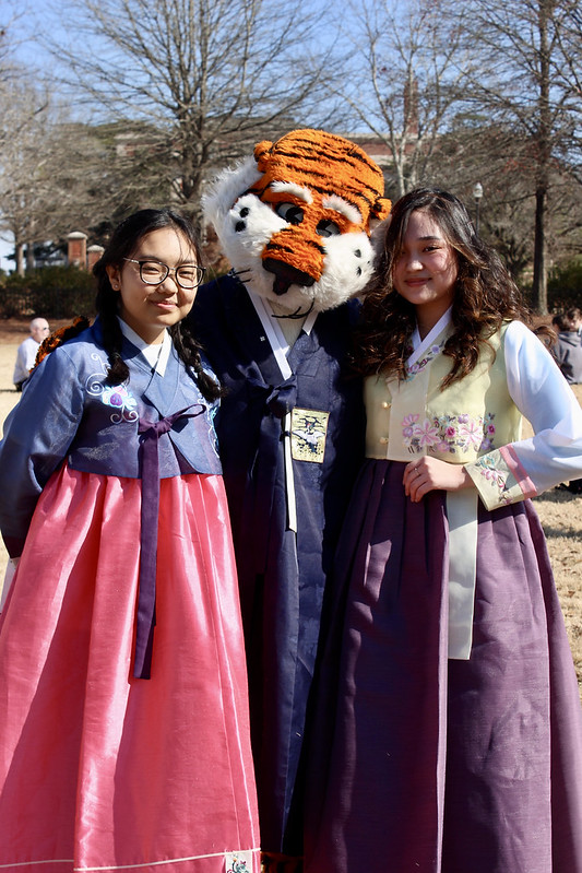 Two students stand on either side of Aubie wearing hanboks
