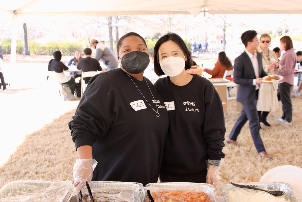 Two Korea Center volunteers take a break from serving food to pose for a photo.