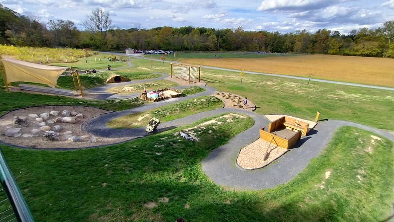 Gravel walkway runs through a grassy area that contains play features. 