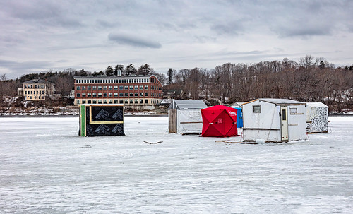 Ice Shacks Also called ice huts, fishing shelters, ice houses, and more.  These are on the Androscoggin River taken from the Brunswick side with Topsham in the background.  Open water is visible and since I took this photo the open water has significantly enlarged and a few of these huts have been removed. We have had a much warmer winter than usual so far.  

An ice shanty (also called an ice shack, ice house, fishing shanty, fish house, fish coop, bobhouse, ice hut, or darkhouse) cabane à pêche (fr) is a portable shed placed on a frozen lake to provide shelter during ice fishing. They can be as small and cheap as a plastic tarpaulin draped over a simple wooden frame, or as expensive as a small cabin with heating, bunks, electricity, and cooking facilities.

More durable ice houses are generally left on a lake for the duration of the ice fishing season, although this can cause problems, such as thaws and re-freezing causing houses to be immoveably frozen onto the lake. Lighter, cheaper versions can collapse into a package to be moved from lake to lake during the season.

Many northern communities have developed bodies of laws about the operation of ice shanties - frequently including dates by which they must be removed, even if the ice can still hold them.[Wikipedia]
